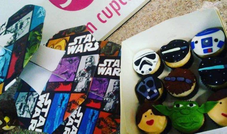An open box of Star Wars cupcakes beside matching Star Wars wrapping paper