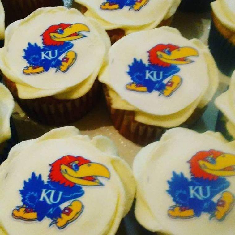 Cupcakes topped with edible Kansas Jayhawk logos on white frosting