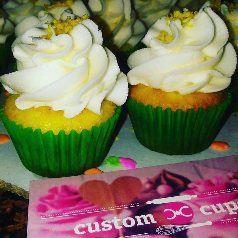 Yellow cupcakes with whipped frosting beside a fresh lemon